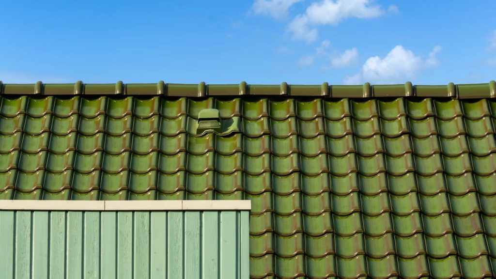 Closeup of a green tiled roof under a bright blue sky, capturing architectural detail and color contrast.